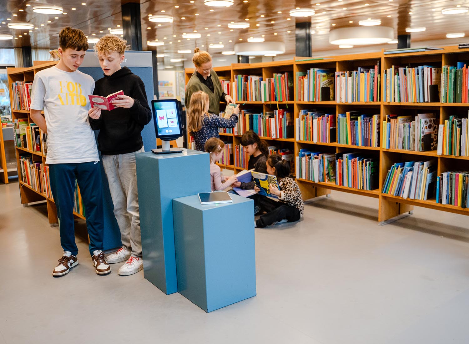 Barn som läser och en bibliotekarie som hjälper till att hitta böcker