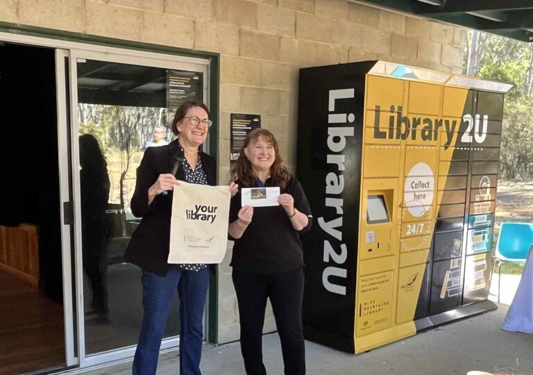 Librarians holding items in front of Blue Mountains Library remoteLocker.